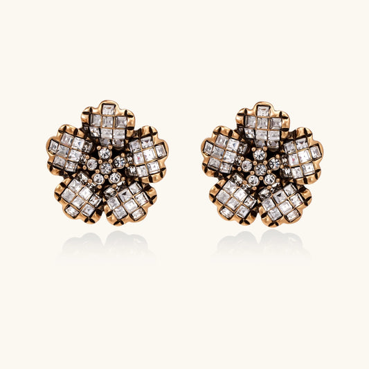 Gold-plated floral stud earrings with geometric zirconia crystals arranged in five-petal design on cream background